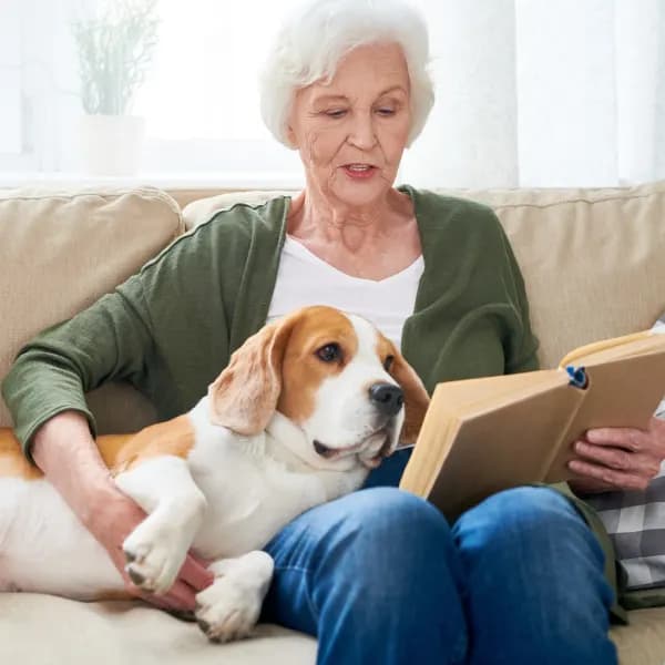 Woman reading a book and holding a dog.